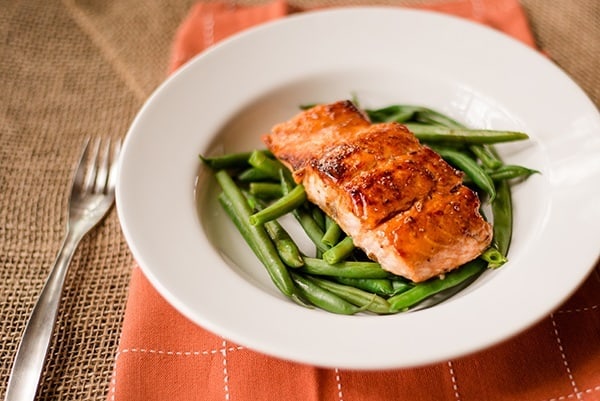 Close up of pan-cooked salmon on a bed of green beans, ready to be served and enjoyed 